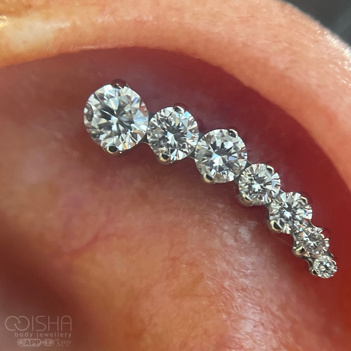 close up of a helix piercing in the ear cartilage with a diamond studded curved cluster earring