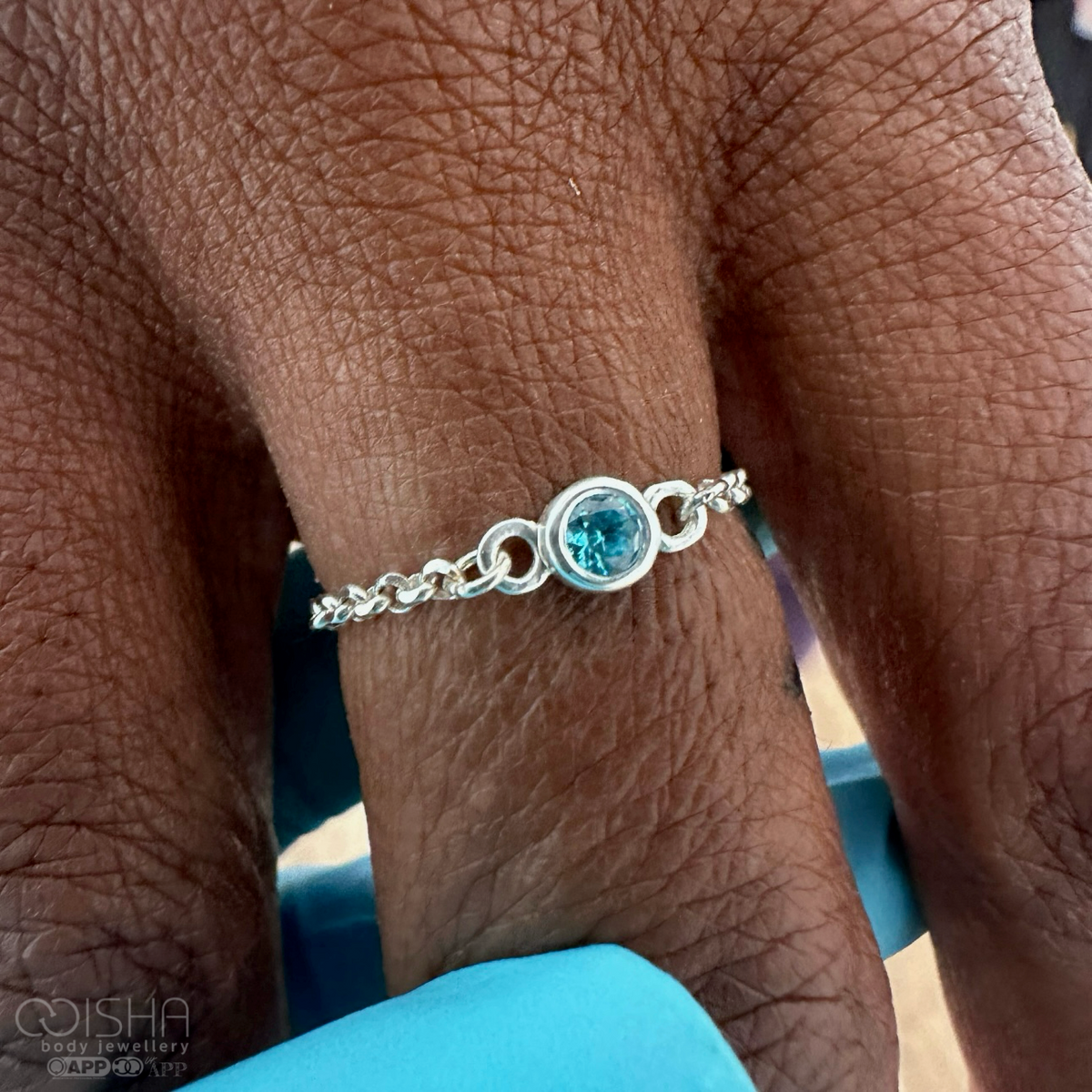 Silver ring with a blue gemstone on a person's finger